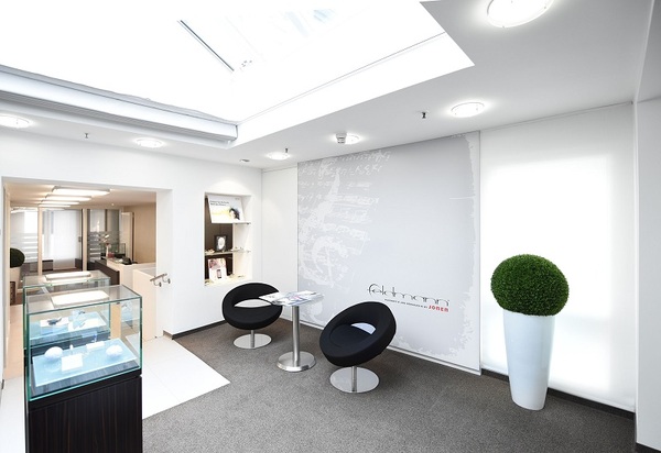 Modernes Juweliergeschäft mit heller Einrichtung, Sitzbereich und eleganter Vitrine.